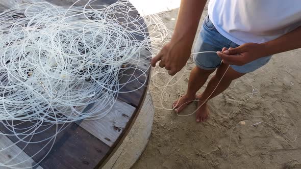 Hands are shown skillfully working to untangle a mess of fishing line ...