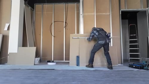 Man Installs Wall with Level in Building