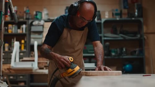 Woodworker Sanding a Cutting Board with a Power Sander in His Workshop