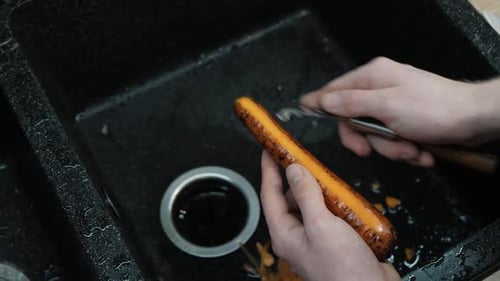 Hands Peeling Carrot in Kitchen Sink