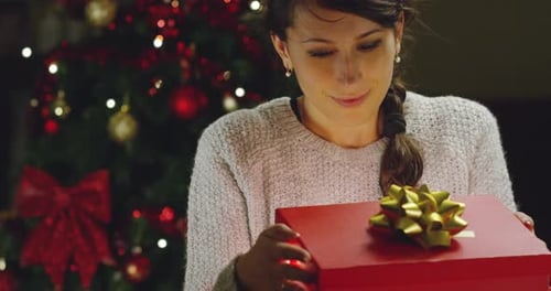 Woman Opens Christmas Gift with Joy and Wonder