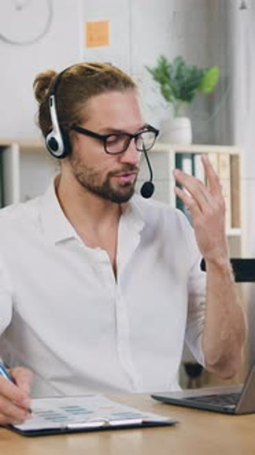 Distant Work Concept Where Likable Man Office Manager in Wireless Headphones Sitting in Front of
