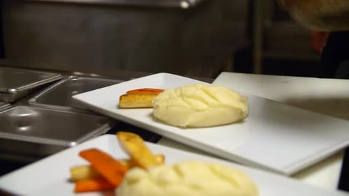 Chef plating food in commercial kitchen with tongs