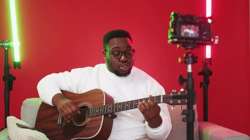 Man Playing Guitar and Recording Himself On Camera