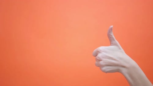 Woman Gives a Thumbs Up on an Isolated Orange Background Hand Gesture Studio Advertisement Approval