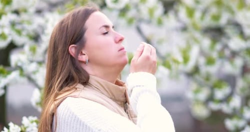 Woman Sneezing with Spring Blossoms in Background