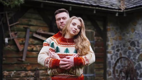 Lovely girl and a guy outdoors. Man hugs girlfriend in the yard.