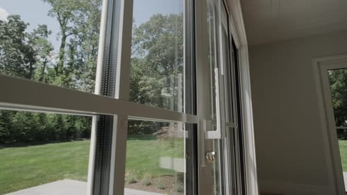 Arbres au feuillage vert par une journée ensoleillée et venteuse vus de l'intérieur d'une fenêtre
