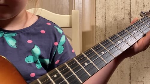 Child Learns Guitar with Adult Assistance Indoors