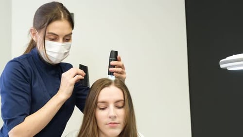 Woman Visiting Dermatologist at Clinic Runs a Trichoscope Over Scalp and Looks Result on Monitor