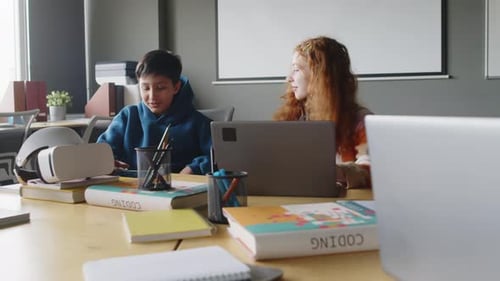 Un garçon et une fille travaillent sur un projet en classe de programmation et donnent des high five