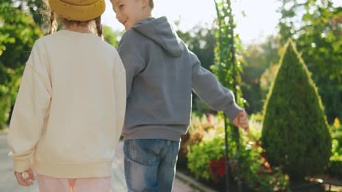 Children Enjoy a Joyful Walk Holding Hands in a Colorful Garden Surrounded By Blooming Flowers on a