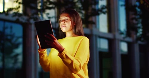 Woman Using Tablet at Night in Urban Setting