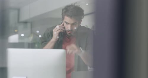 4k video footage of a young businessman using a smartphone and computer in a modern office