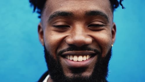 One young black man smiling at camera, tight close-up face. Joyful African American 20s person