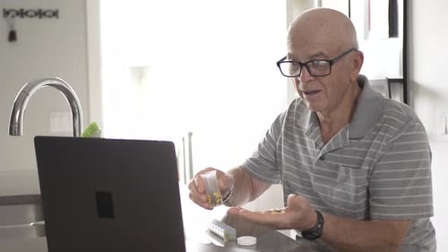 Senior Man Preparing Medications with Telehealth Appointment