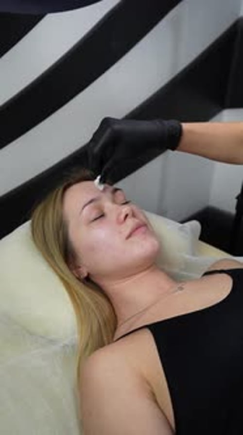 Hair removal master applies wax on client's face. Eyebrow correction with wax. Close up