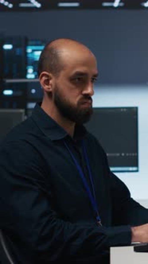 Man Types at Computer in Server Room