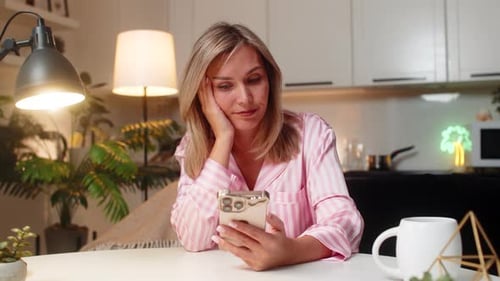 Woman in Pajamas Using Phone at Home