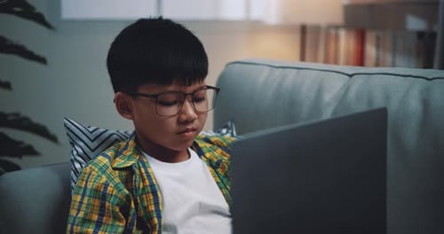 Asian boy wearing glasses schoolboy using a laptop computer