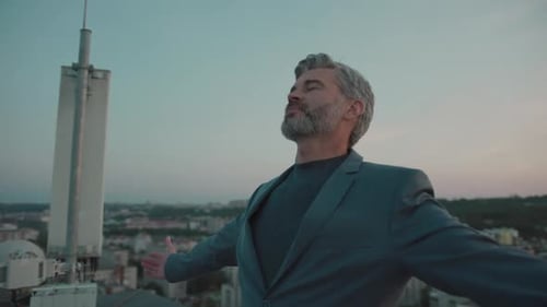 Attractive Business Man in Suit Standing Feel Freedom Raises Hands on Roof Top at City Skyscraper