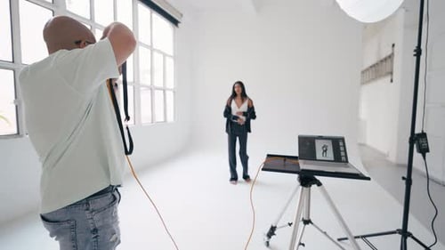 Photographer Taking Pictures of Model Posing in White Studio