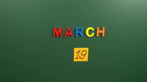 Hand sticking a sticker 19 March calendar day on school board. 19 date of March. Nineteenth day