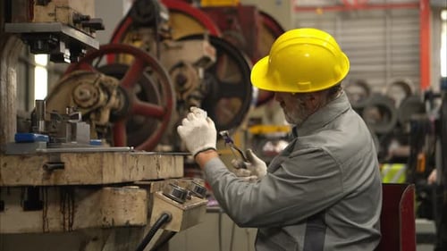 Senior experienced technician checking and maintenance a large machine in metal sheet factory