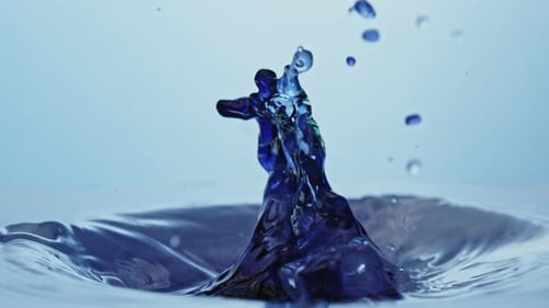 Un glaçon éclabousse de l'eau propre créant une fontaine violet foncé. filmé Ralenti 4K