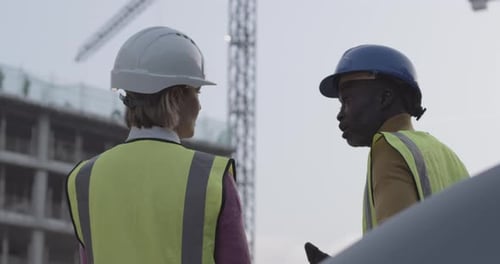 Engineer and architect meeting on building construction site discussing development