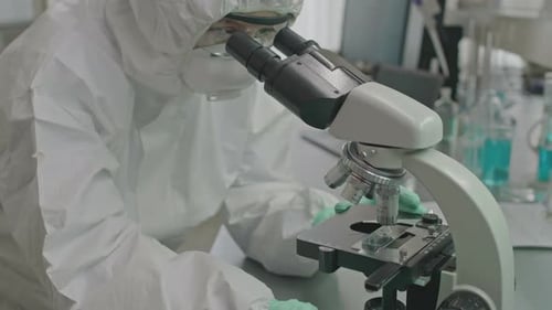 Scientist Using Microscope in Lab with Protective Suit