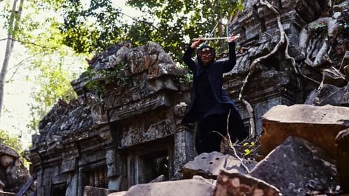 Masked Figure with Staff Poses Among Ancient Ruins