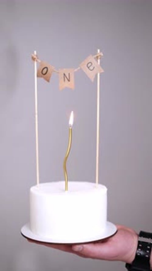 Small White Cake with Candle Held in Hand