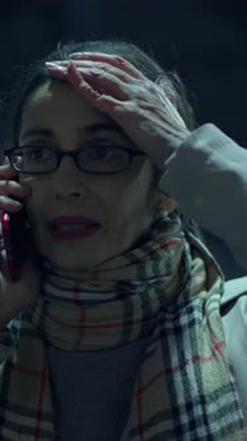 An Anxious and Concerned Woman on the Phone in a Dark Environment Within an Urban Cityscape