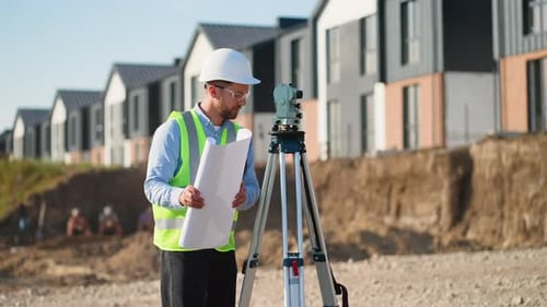 Construction Worker Using Theodolite on Construction Site