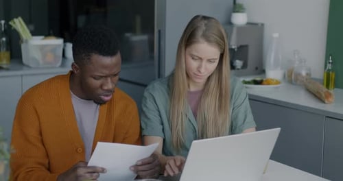Caucasian Woman and African American Man Using Laptop Typing and Reading Paper Document Sitting at