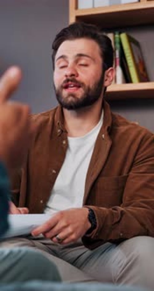 Bearded Man Talking and Writing on Paper Indoors