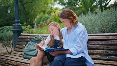 Child and Woman Reading a Book on Park Bench