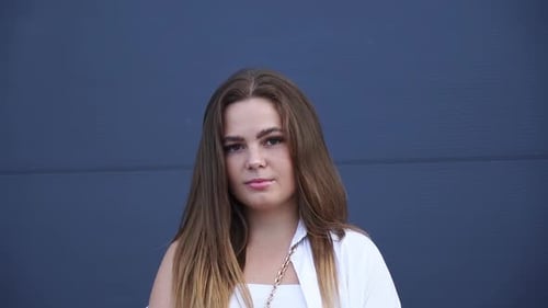 Portrait of young Caucasian girl in white shirt posing for camera. Close-up.