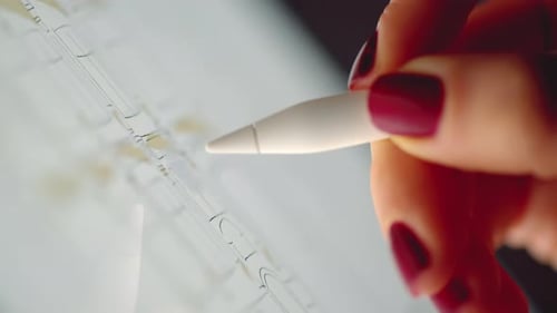 Woman hands painting with white pencil on tablet pc at night