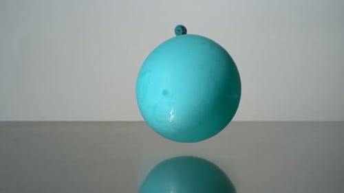Turquoise Water Balloon Bursting in Slow Motion