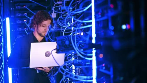 Man Working on Laptop in Server Room
