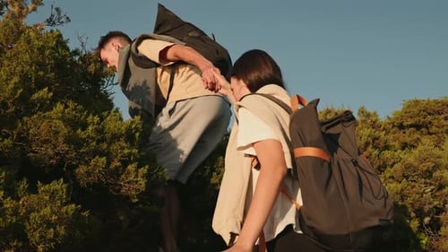 Couple Hiking and Helping Each Other on Steep Hill