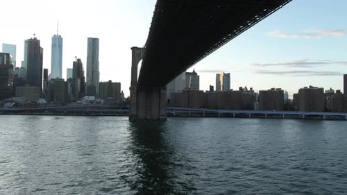 Wide angle aerial tracking shot underneath the Brooklyn Bridge with downtown Lower Manhattan, New Yo