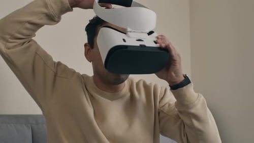 Close-up of man adjusting VR headset in a modern home setting, showcasing tech lifestyle