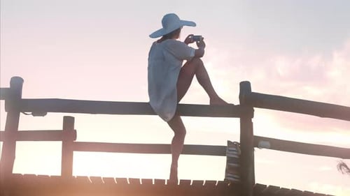 Independent woman captures tropical sunset on pier with smartphone at paradise resort