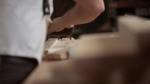 Man Shaping Wood with Hand Plane in Workshop