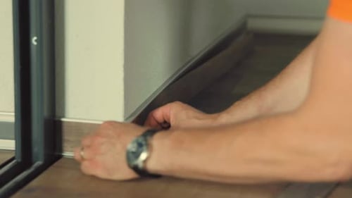 Man Installing New Laminate Flooring in Room