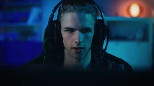 Gamer in Headset with a Mic Playing Online Video Game on His Personal Computer. He Actively Monitor