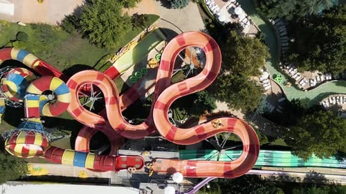 Aerial View of Colorful Twisting Water Slides with People Riding Inflatable Tubes at a Water Park